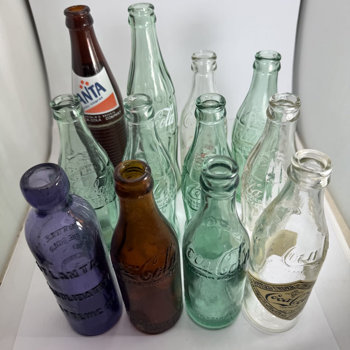 12 Coca Cola (and related) Bottles: Various base marked Coke Buddies (Newcastle, Oakland, Barre) Fanta & 10 oz ceramic labels. Amber straight sided from Memphis (badly damaged) Commemorative bottles Zapped Hutchinson patent from Atlanta Consolidated Bottling - not coke but from the home of coke!