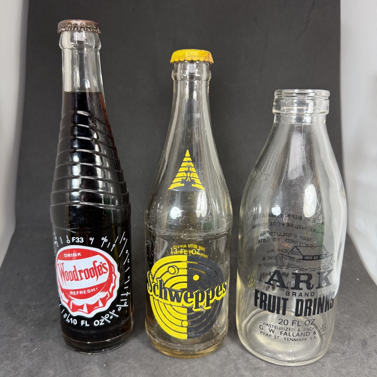 3 Ceramic Label Drink Bottles: Woodroofe's 10 oz still sealed with contents; Schweppes 13 oz with loose fitting cap; Ark Brand Fruit Drinks, Falland & Co Renmark.