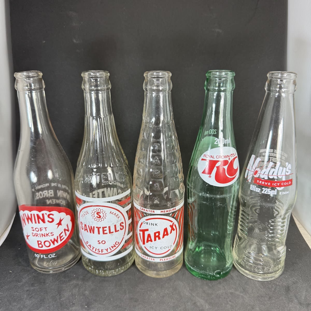 5 Ceramic Label Crown Seals: Unwin's Bowen; Sawtells Kingaroy; Tarax; Royal Crown RC Cola; Noddy's Melbourne & Geelong.