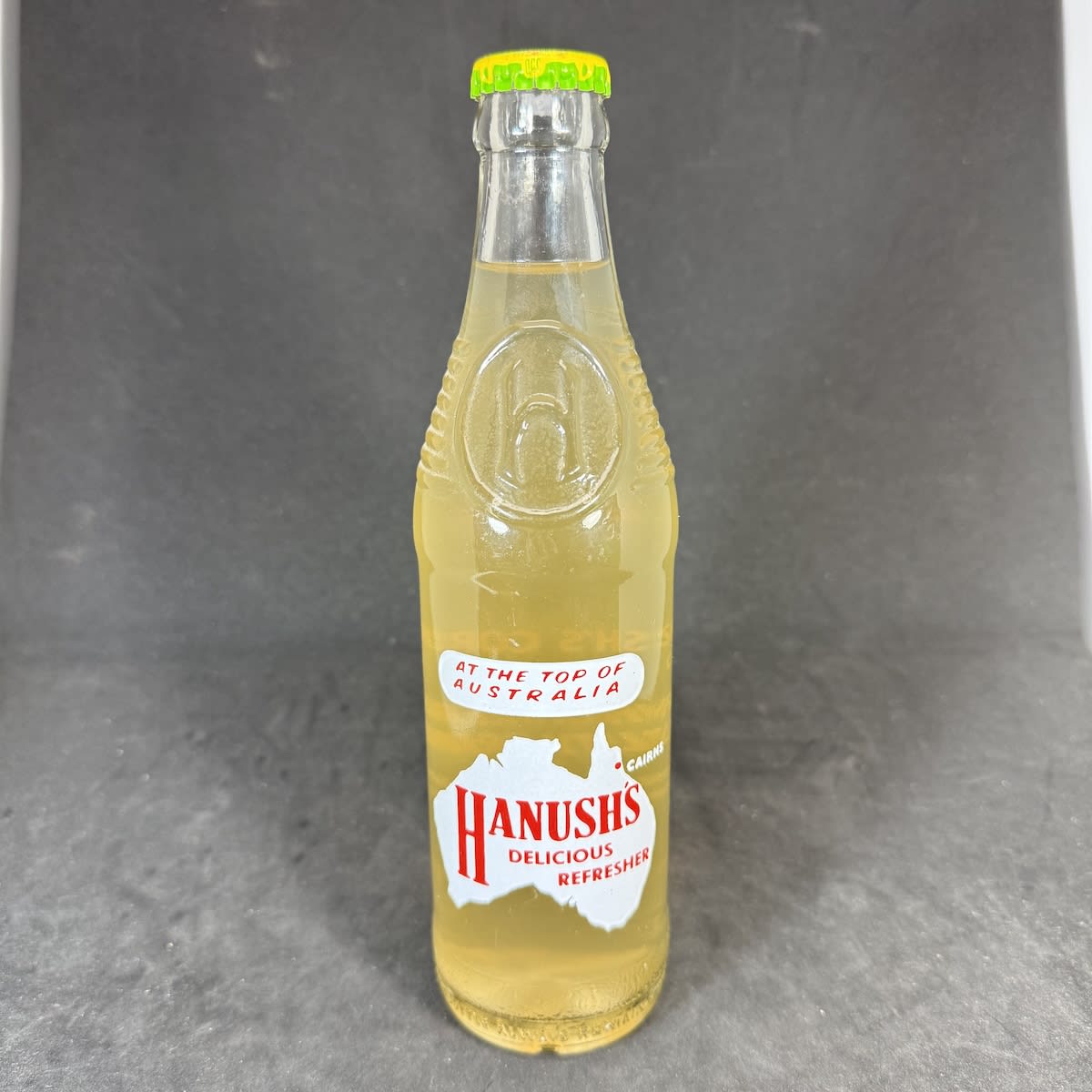 Ceramic Label Crown Seal. Hanush's Cordials Cairns. Delicious Refresher. Larger Bullet shape. Sealed with contents and Hanush's Pineapple Flavour cap. (Queensland)