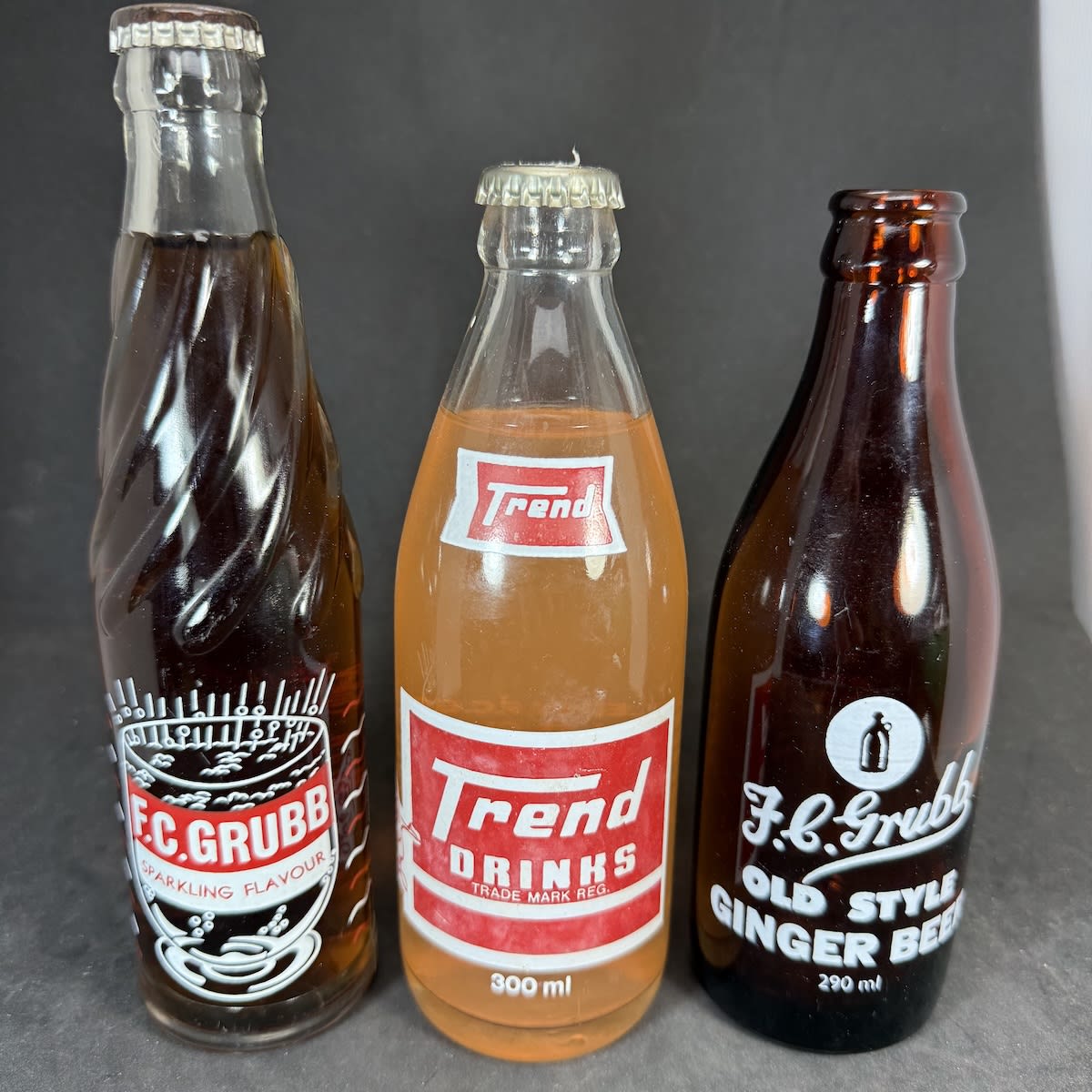 3 Ceramic Label Crown Seals all from F. C. Grubb, Gladstone. Tall fancy one sealed with Cola cap; 300 ml with generic plain cap and an orange drink inside. (South Australia)