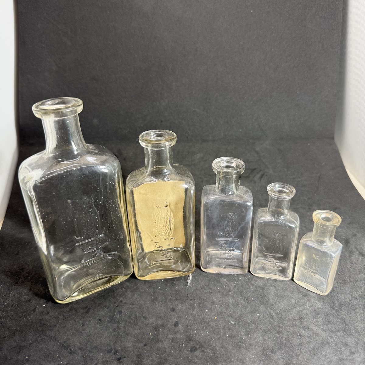 5 Owl Drug Co Bottles. Single & Double Wing Owls. 2nd largest with original label for Glycerine. Clear. Machine made and spun finished tops. 67 - 155 mm.