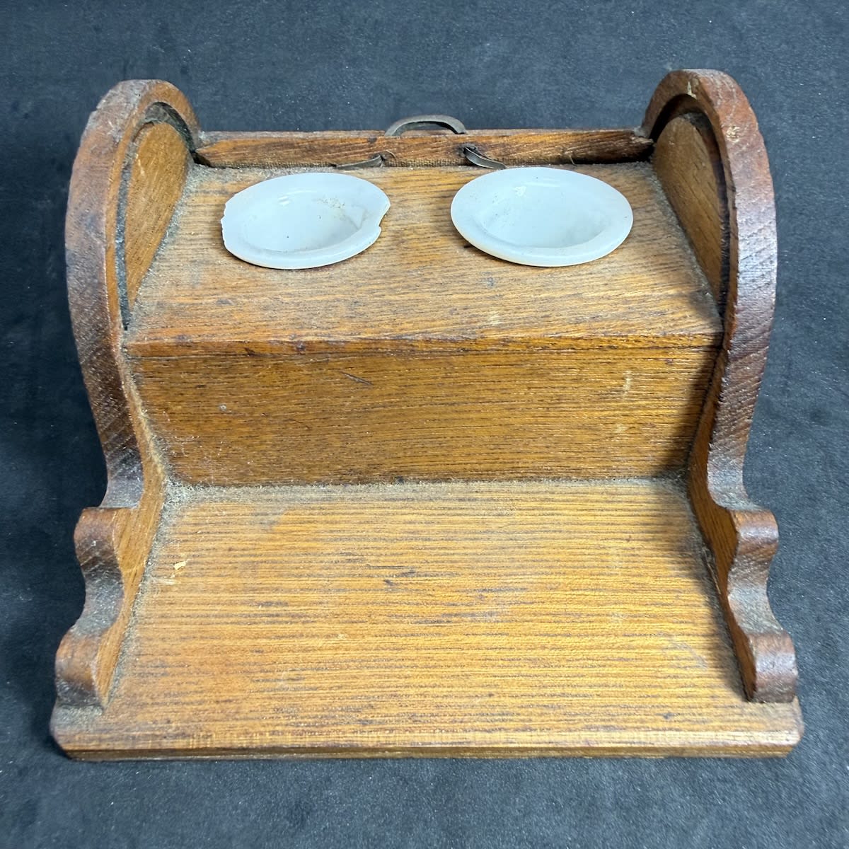 Inkwell. Desk inkwell in the shape of a desk. Roll top section that covers the inkwells. Two penrests at the front. Removable porcelain inkwells in holders in the top part.