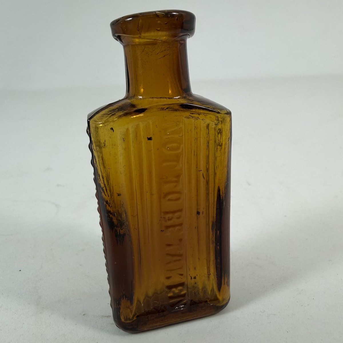 Poison. Not to be Taken. Amber. 1/2 oz. Grooves either side of embossing and two columns of crosses down each side. 73 mm. (South Australia)