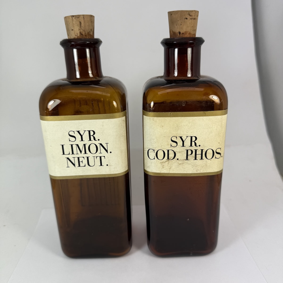 2 Chemists Bottles: Square Amber with labels for Syr. Cod. Phos. & Syr. Limon. Neut. Wellcome Chem Works to base. One has three sides with vertical grooves.