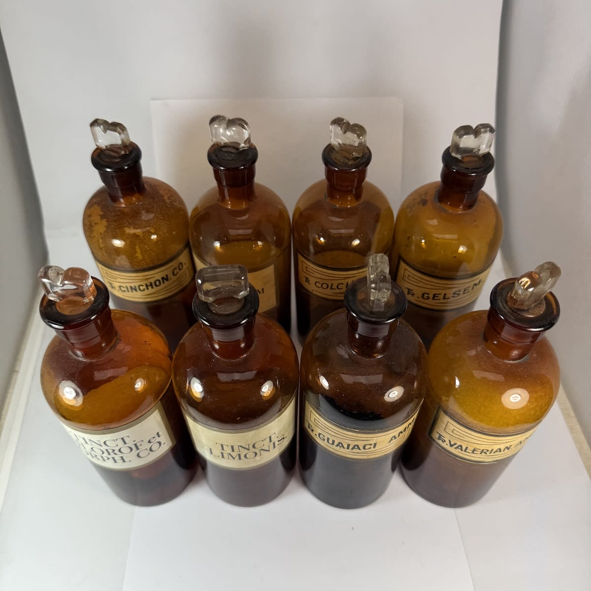 8 Stoppered Chemist bottles. Original labels, half with labels on two sides. Amber. With stoppers.