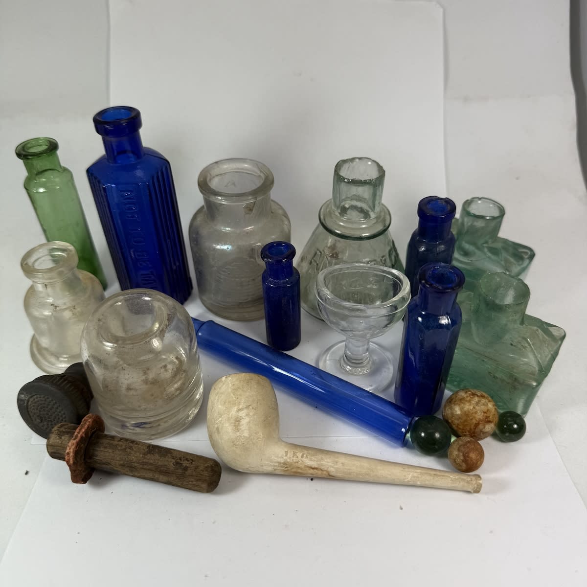 Multiple Items: Inks; Clay Pipe; Blue Poisons; Long blue powders bottle; Eye Bath; Stoppers; Marbles.