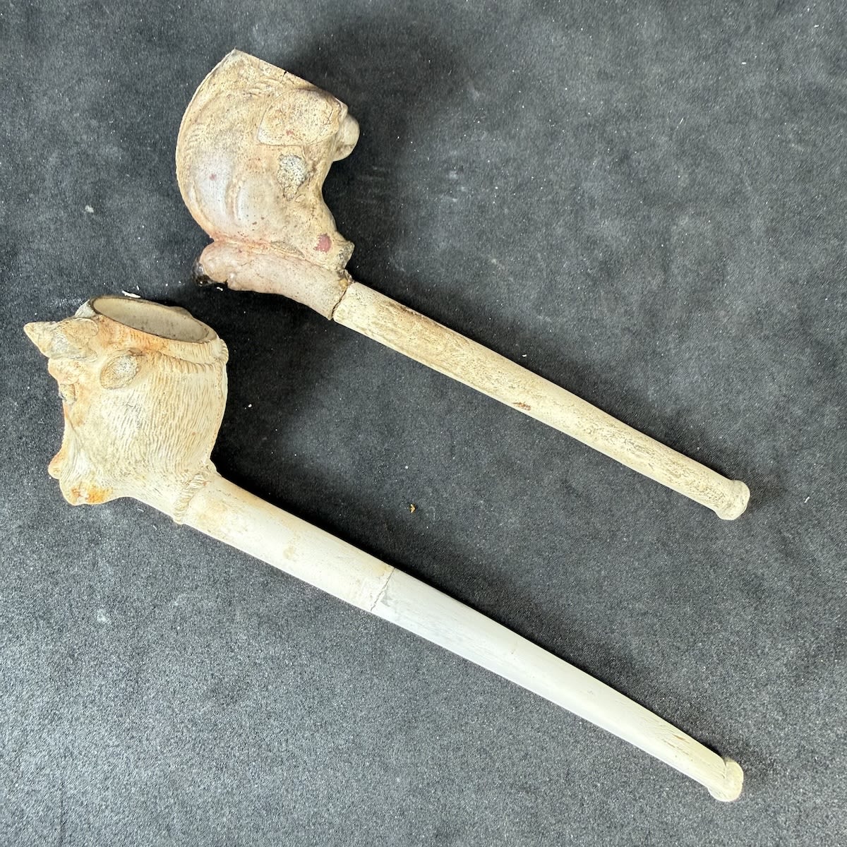 2 Clay Pipes: Cows Head; Boars Head facing back at the smoker. Both with repaired stems.