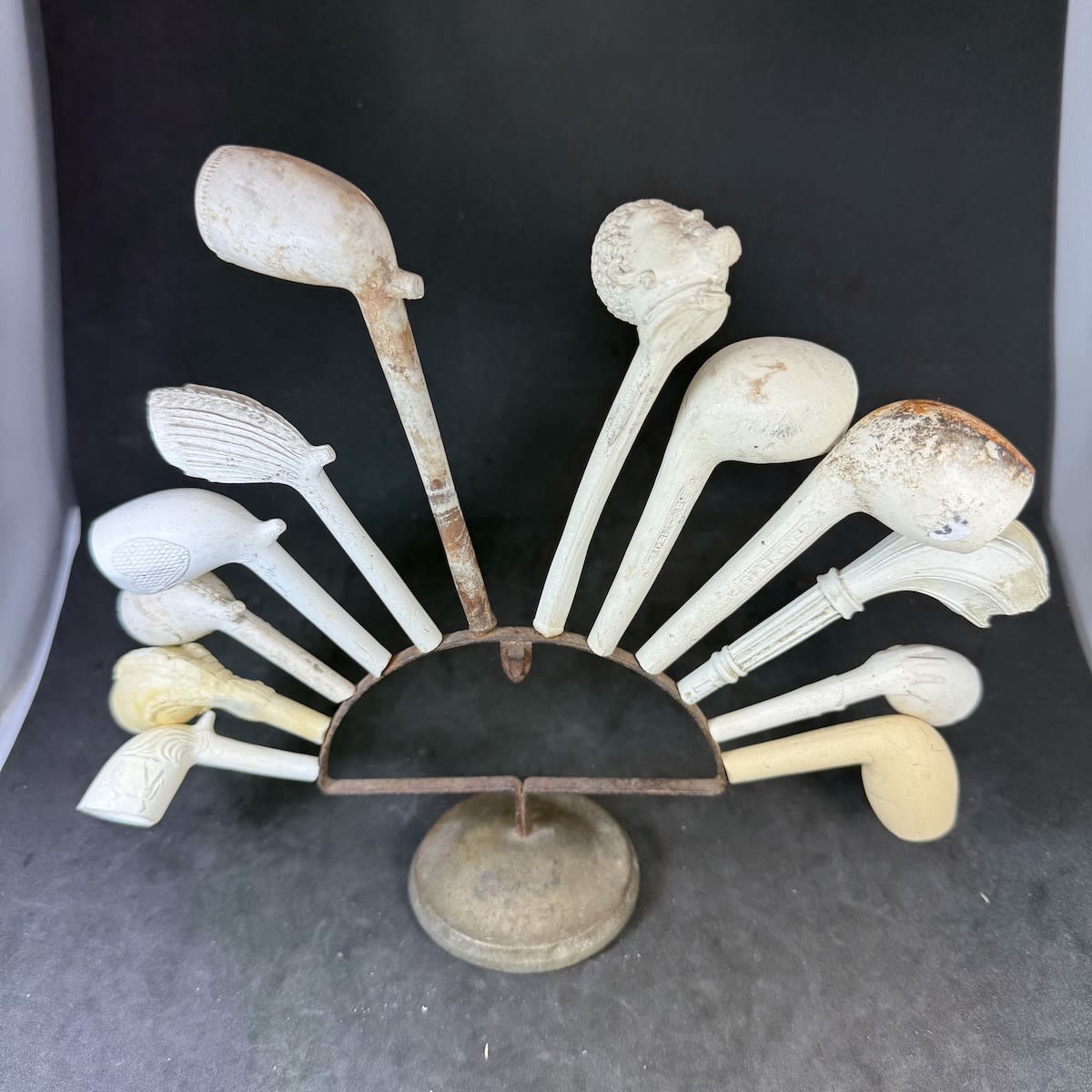 Metal Tobacco Pipe Stand with weighted base AND with 12 clay pipes - 2 complete and 10 with broken stems. Includes a nice complete figural pipe and a pipe bowl and part stem of an Australian "Squatter" pipe.