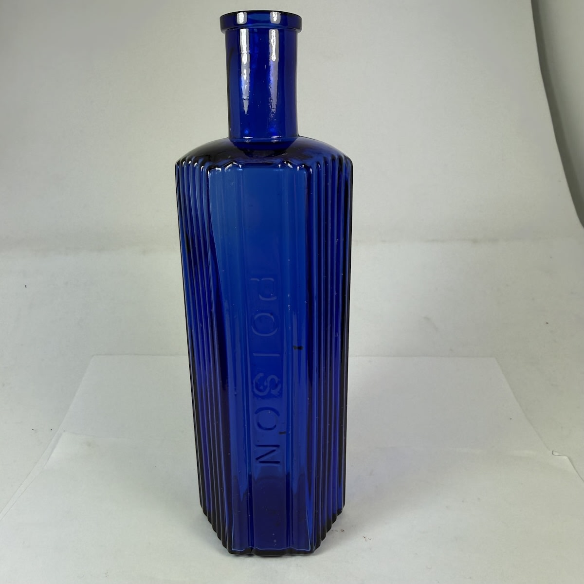 Poison. Hexagonal Cobalt Blue Poison. Vertical grooves either side of embossed panel. 884 to base. Tall slender bottle. 163 mm. 6 oz.