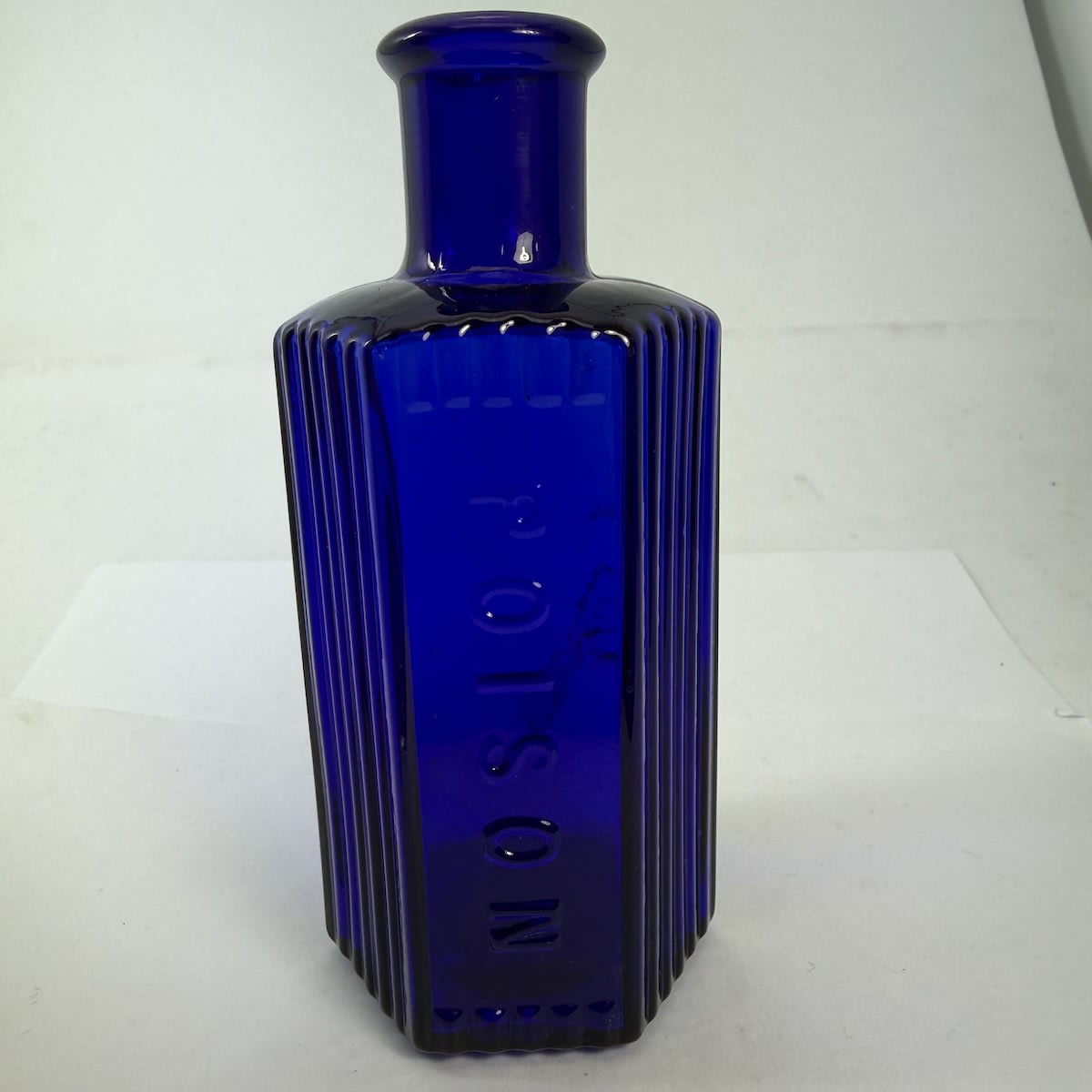 Poison. Hexagonal Cobalt Blue Poison. Vertical grooves around and either side of embossed panel. 4 to base. 114 mm. Squat wide type.