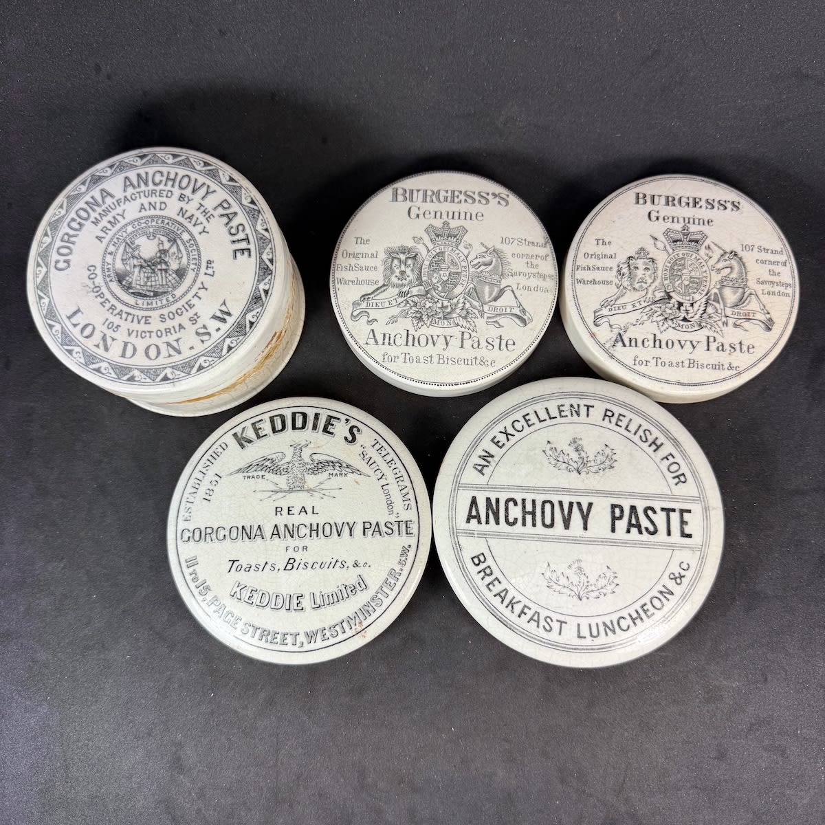 5 Anchovy Paste Pot Lids: Army & Navy Co-operative (with a base); 2 x variations of Burgess's; Keddie's; Generic Excellent Relish.