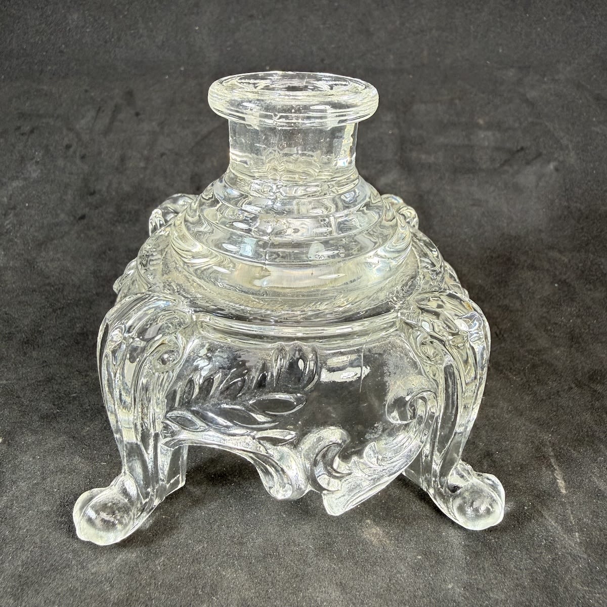 Inkwell. Crude machine made moulded ink. Four feet with raised and highly decorated middle.