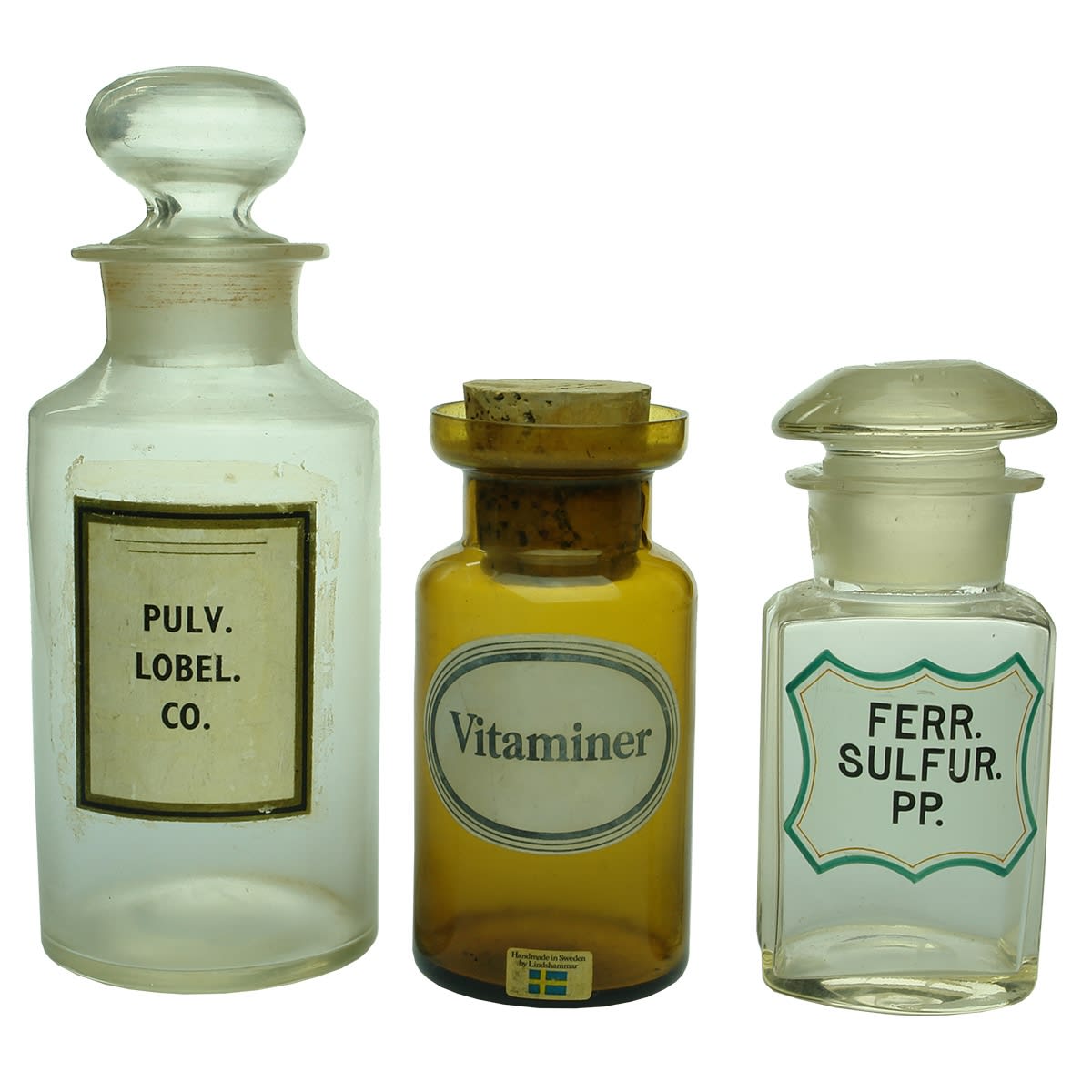 Chemist. 1. Pulv. Lobel. Co. Paper label on large clear stopper jar with pontil. 2. Vitaminer. Handmade in Sweden by Lindshammar. Amber jar with unusual wide flared lip. 3. Ferr. Sulfur. PP. Clear small curved oblong jar with enamelled print.