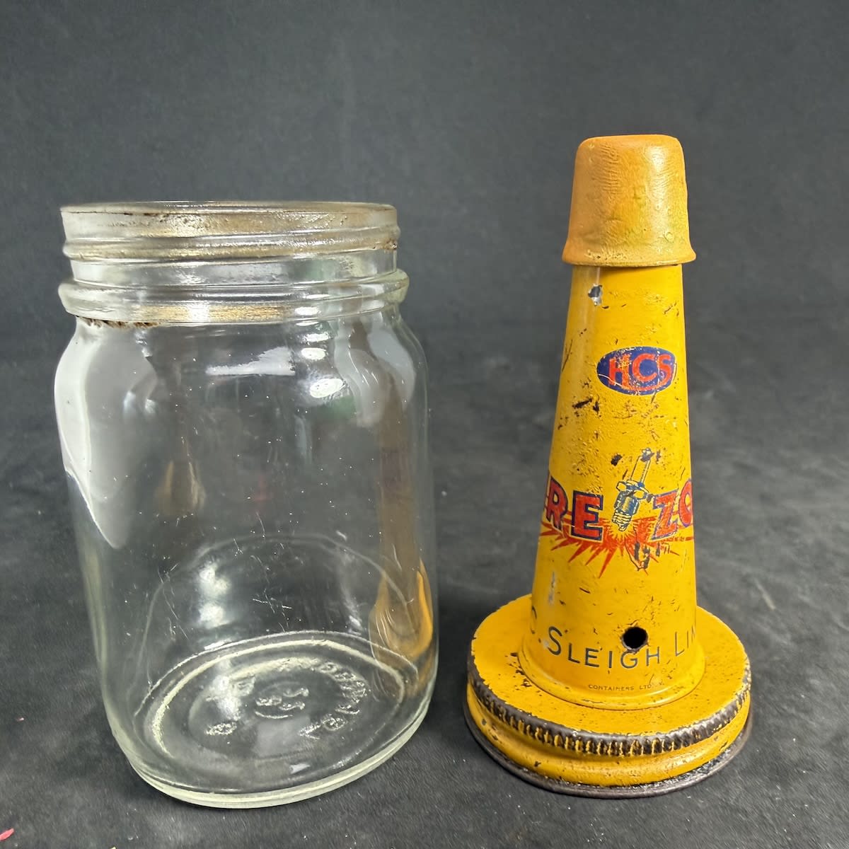 Tin pourer on small glass jar. HCS Firezone, Sparkplug, H. C. Sleigh Limited. Modern AGM Monogram based jar.