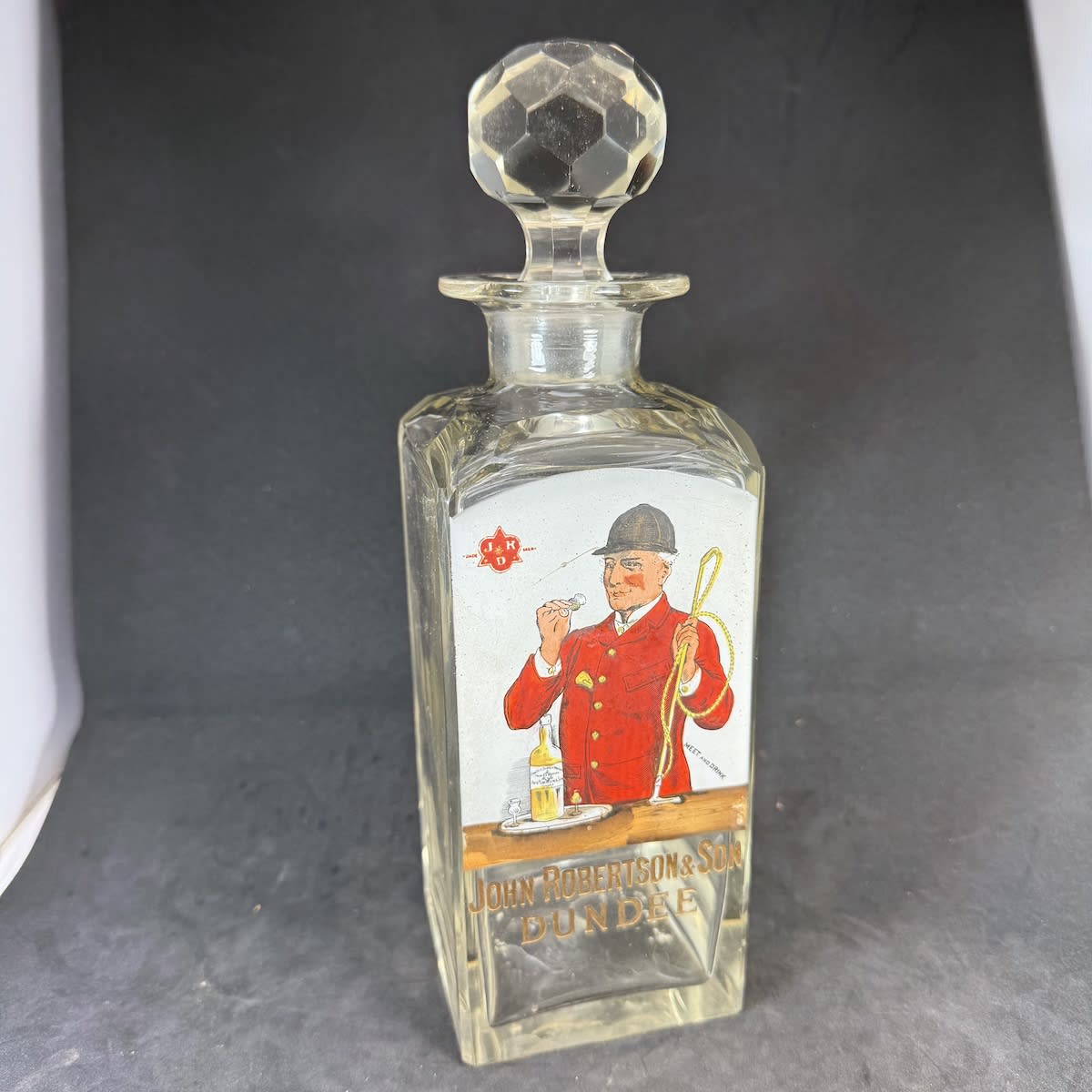 Whisky Decanter. Enamel print of a Huntsman with whip and having a shot of whisky. John Robertson & Son Dundee. With Original stopper.