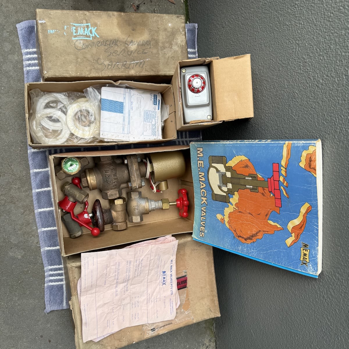 Multiple items from M. E. Mack including original valves, thermostat and catalogue. Some unused parts with receipts for Yarram Laundry Service.