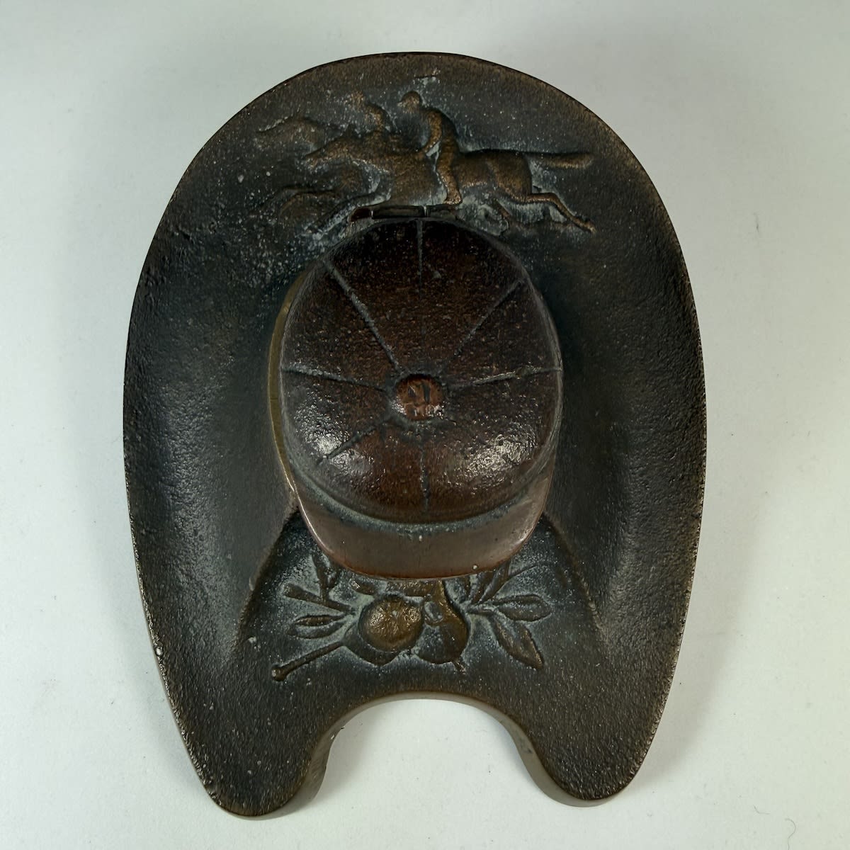 Heavy brass inkwell. Horseshoe shaped. Two racehorses with jockeys, Cap as lid of the inkwell, Cap, Saddle & Whip.