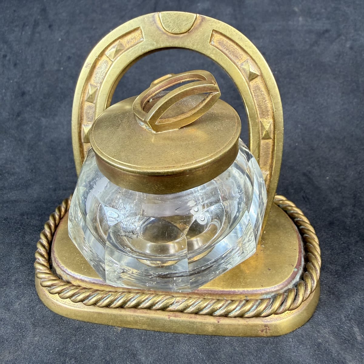 Brass Horse themed inkwell & Pen stand. Cut glass inkwell. Brass lid with a stirrup as handle. Horseshoe frame and two loops to hold pens.