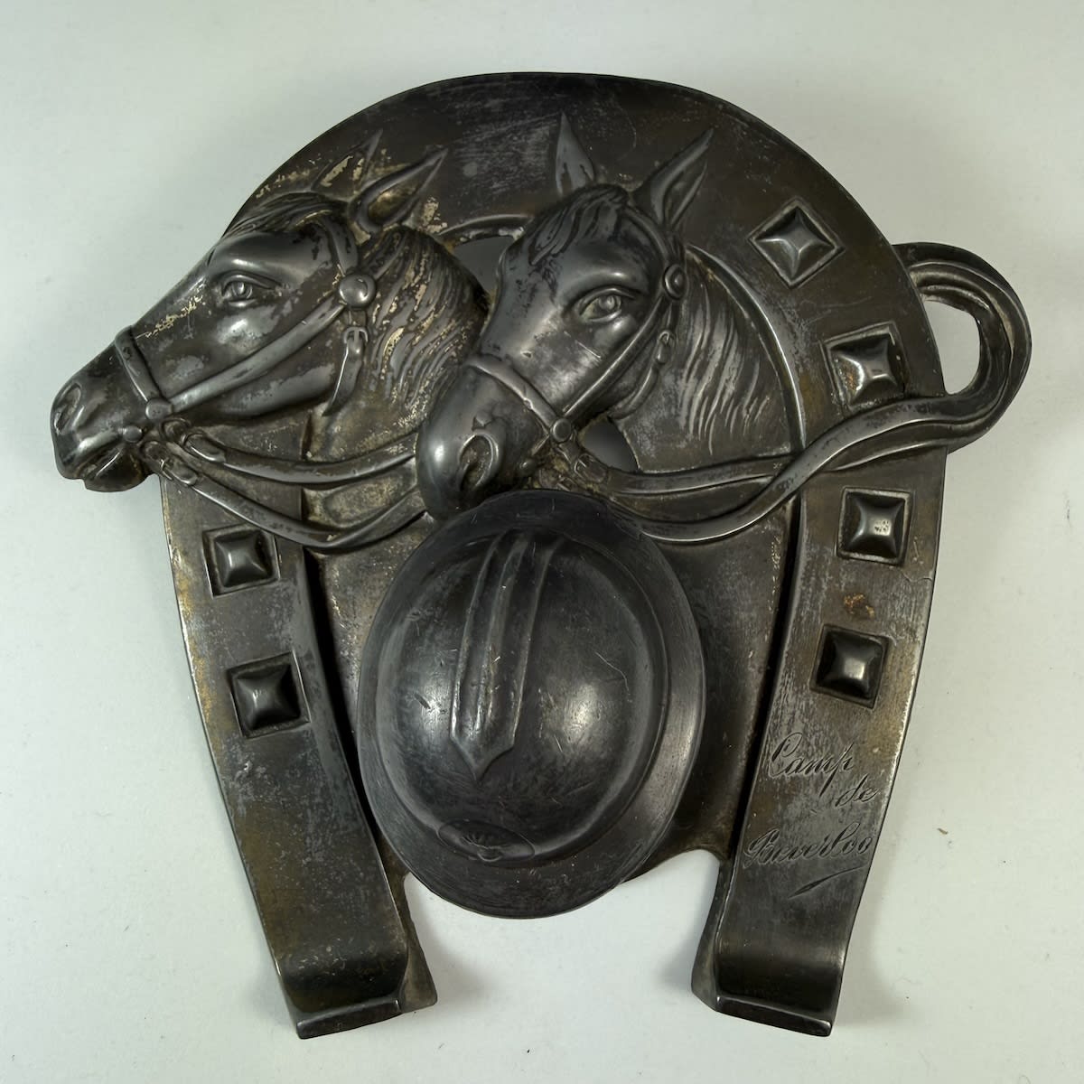 Pewter Inkwell. Horseshoe, Two Horses. Cover of the inkwell is a military helmet with bomb badge to the front. Camp de Beverloo engraved on one side (Belgium).