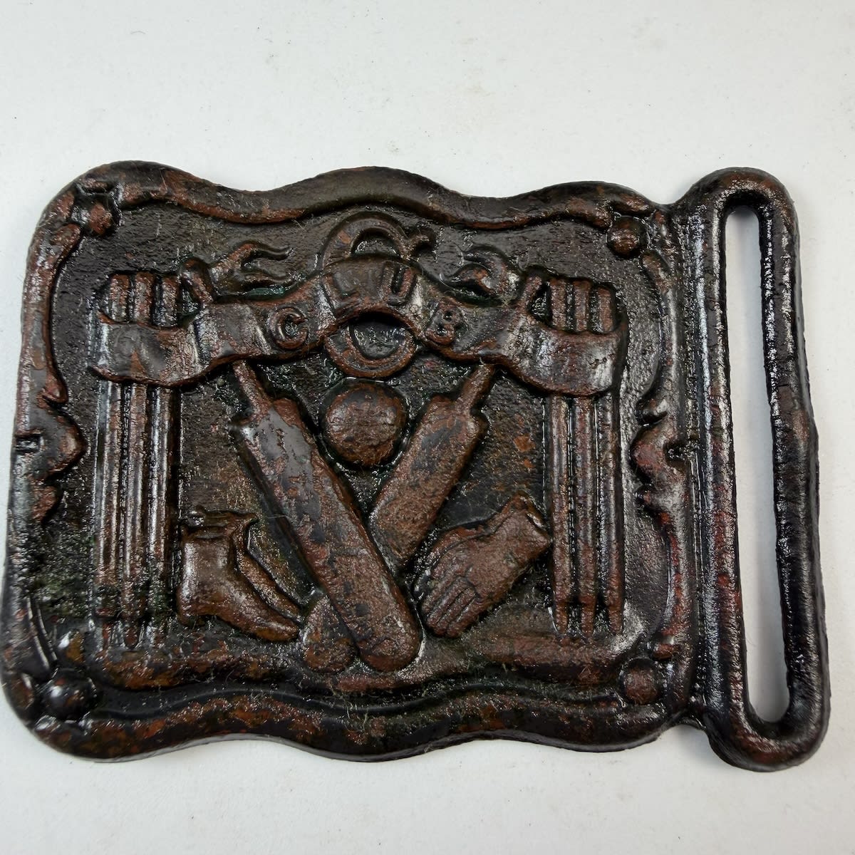 Cricket Belt Buckle / Sash Buckle. Club in a banner. Crossed bats, two sets of stumps, gloves, boots, ball.