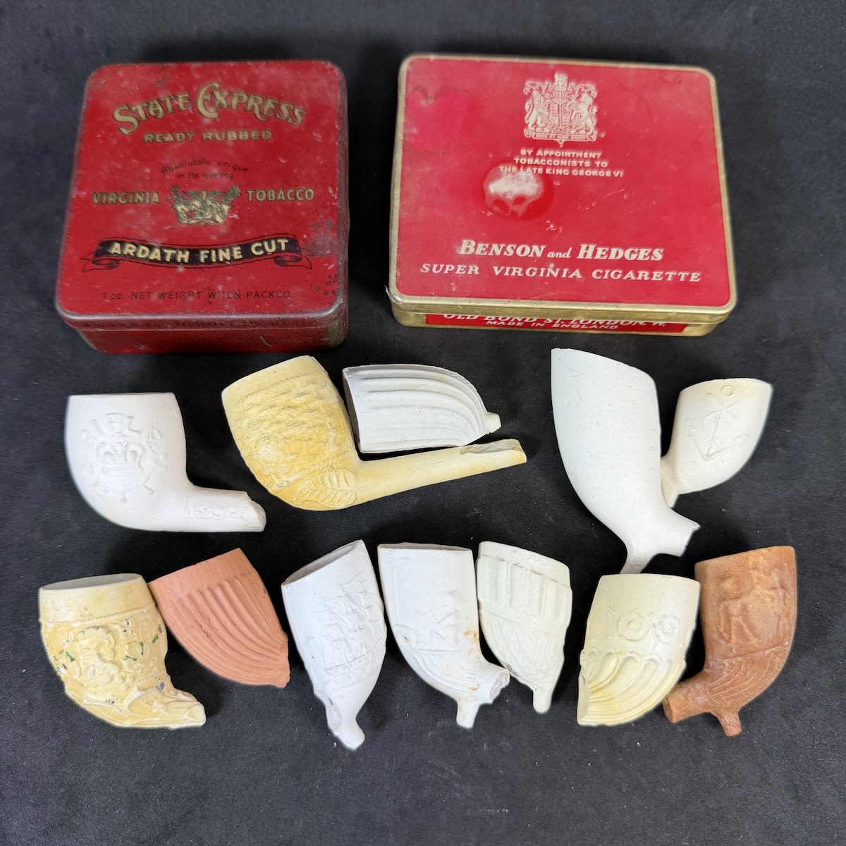 2 Tins and 12 clay pipe bowls. One of the tins actually also has pins and two little tube containers in it.