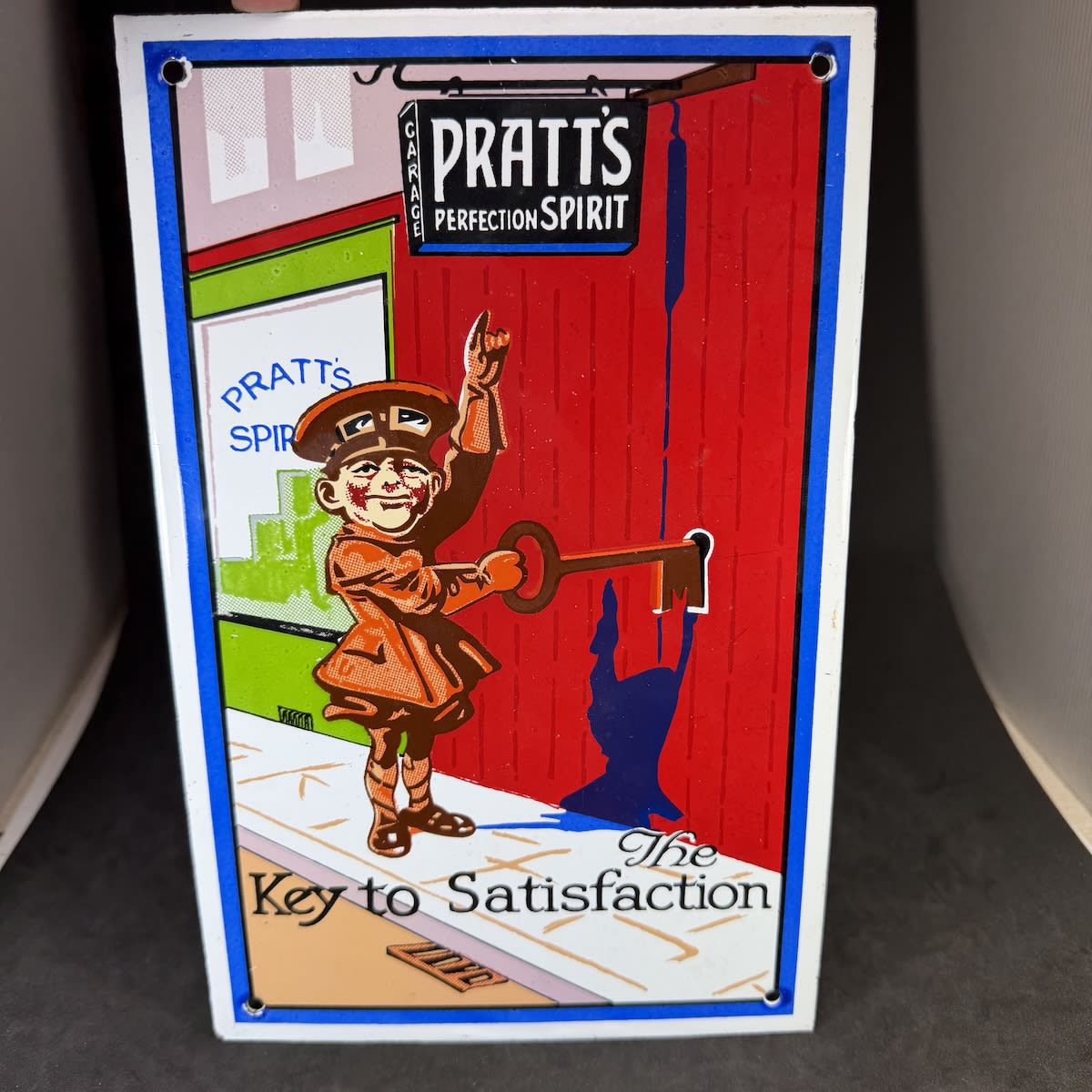 Reproduction enamel sign. Pratt's Perfection Spirit. The Key to Satisfaction. Driver with a large key at a Pratt's Spirit Garage.