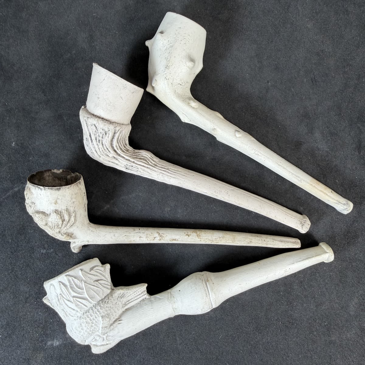4 Complete Clay Pipes: Rough Nobbled one; Wood like texture; Flowers & Leaves; Jungle with Crocodile / Alligator / lizard around bowl.