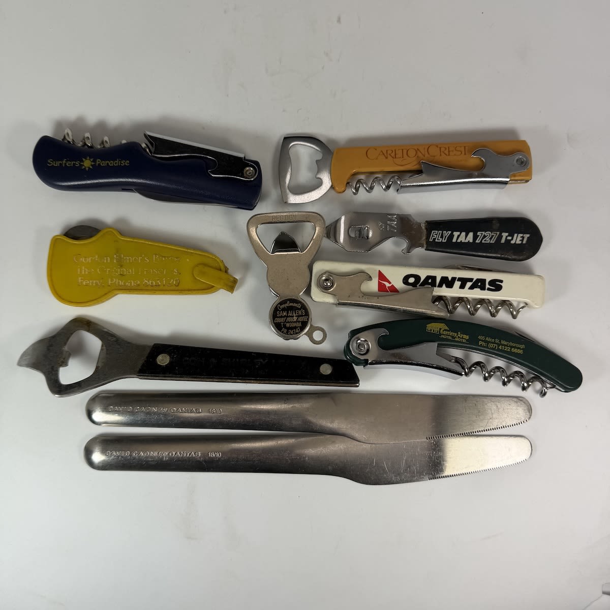 10 items: 8 advertising/promotional bottle openers and 2 Qantas knives.