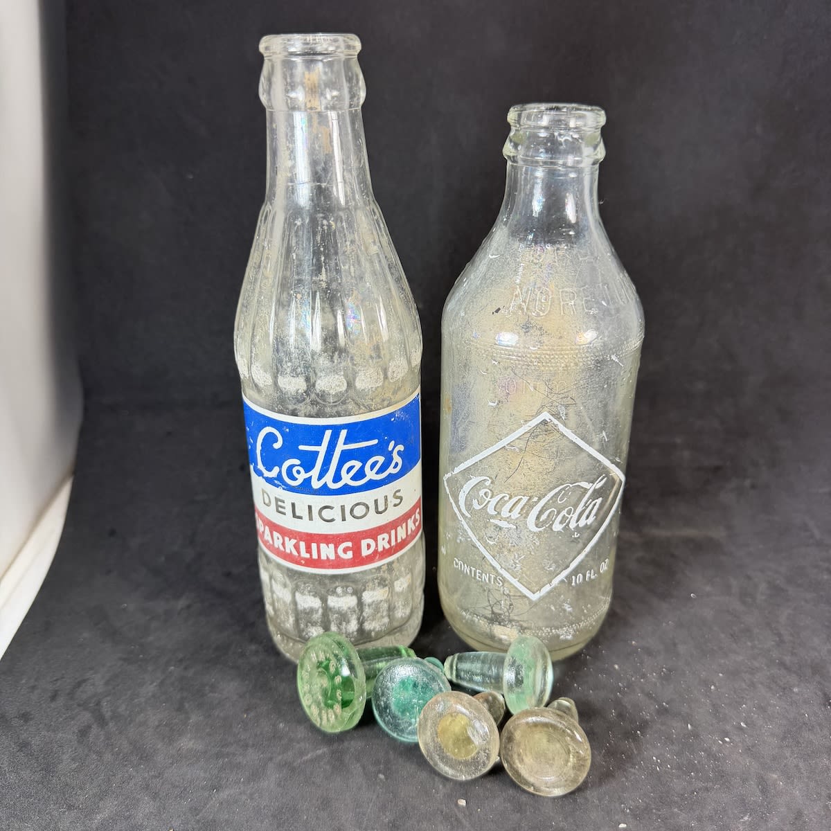 7 Items: Ceramic Label Crown Seals from Coca Cola and Cottee's; 5 glass stoppers.