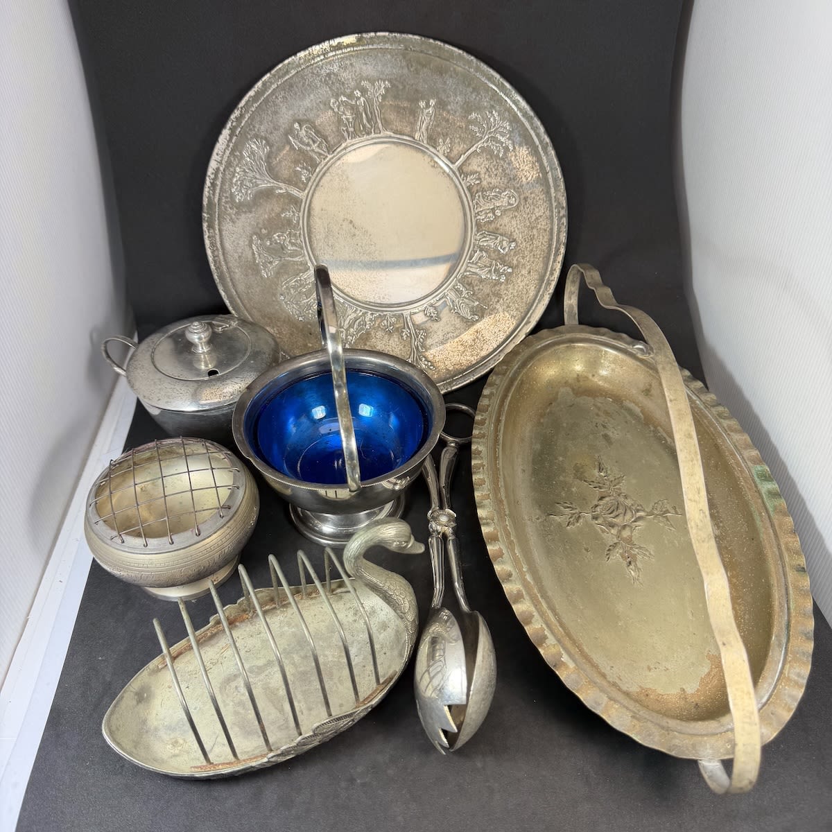 7 Medium to larger pieces of plated metalware. Plate, Swan shaped toast rack, bowls, tongs, etc.