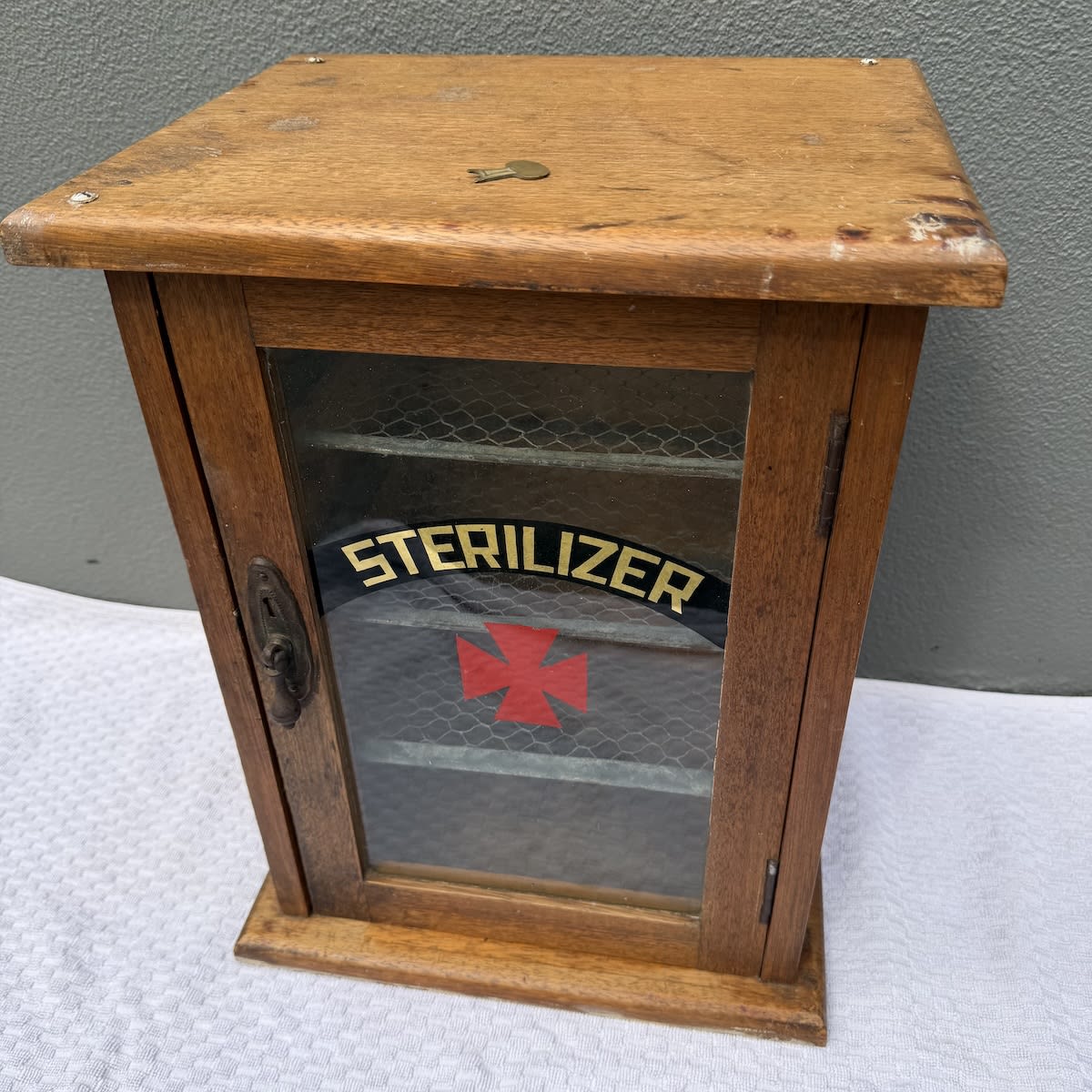 Small Wooden Cabinet. Sterliizer. Red Cross. Three original wire shelves inside.